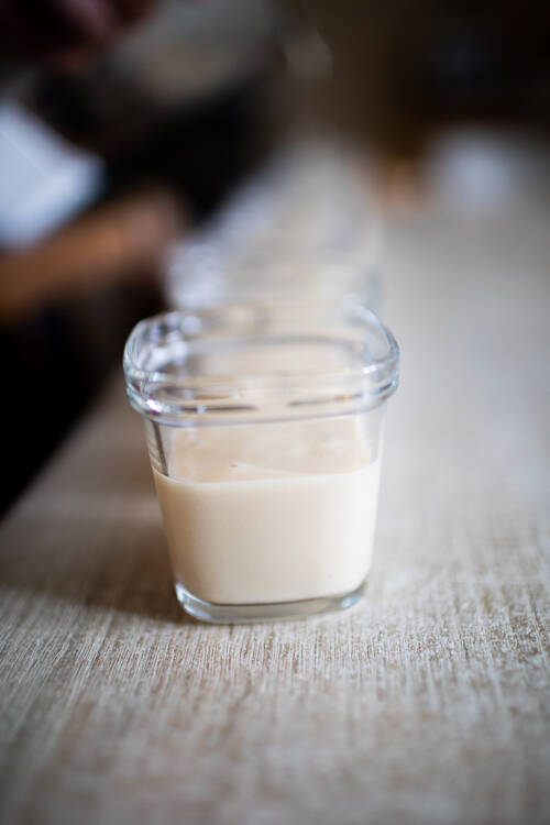 Une dizaine de pots alignés avec de la crème vanille à l’intérieur.