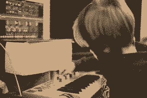 A kid playing with a keyboard in front of a computer