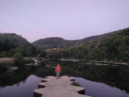 A child walking on a concrete block in the middle of a river